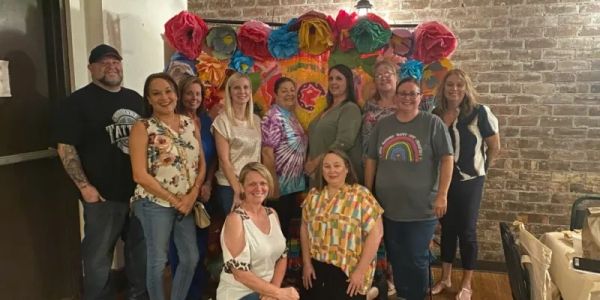 Group photo of smiling people with colorful decorations.