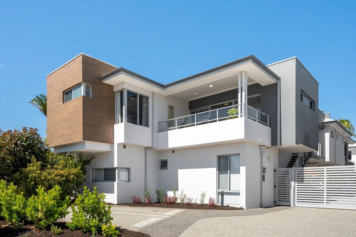 Modern two-story house with white and wooden exterior under clear blue sky.