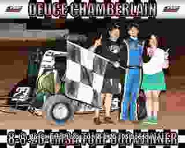 Four people celebrate with a checkered flag next to a race car.