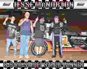 Four men posing in front of a race car with Jesse McNorton banner.
