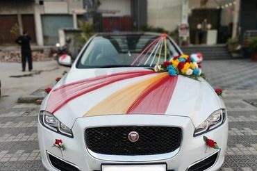 White Jaguar decorated with colorful flowers and ribbons for a celebration.