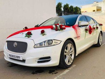 White Jaguar car decorated with red and white flowers for a wedding.