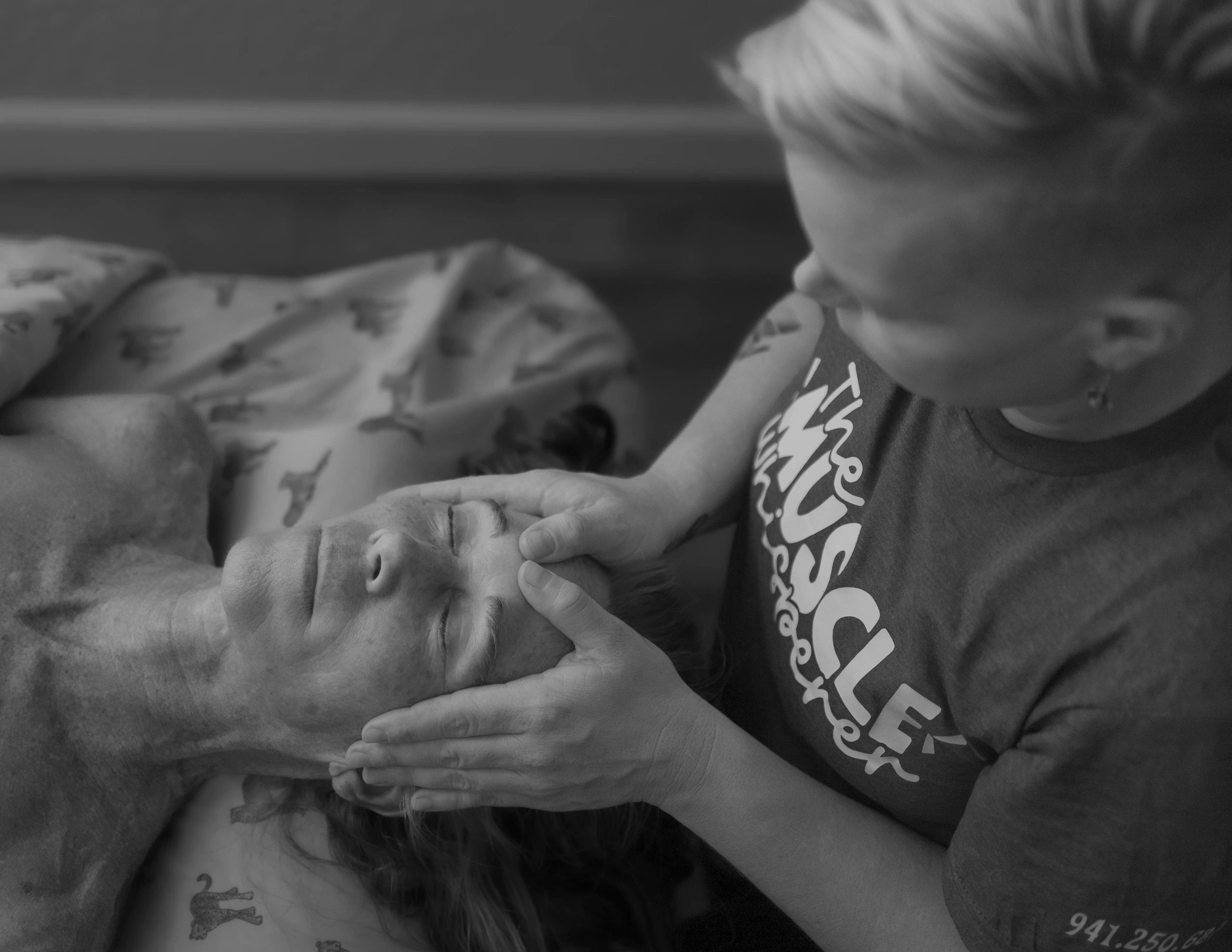A person giving a facial massage to another lying down.