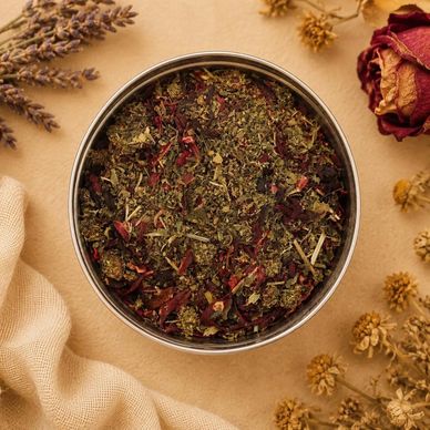 Herbal tea blend in a round container with dried flowers.