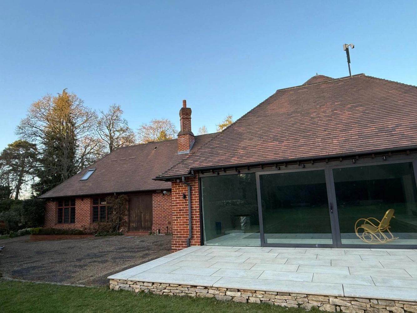 Modern brick house with large glass doors and a rocking chair.