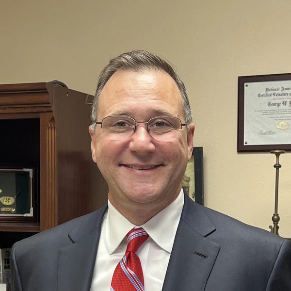 Man in suit and red striped tie smiling indoors.