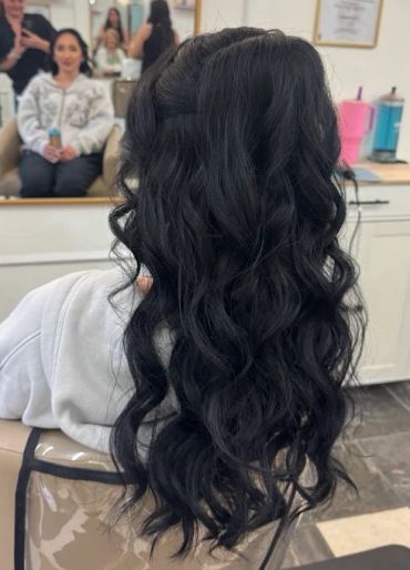 Long, wavy black hair styled in soft curls.