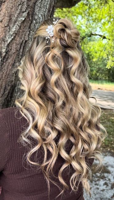 Long curly blonde hair with a floral hair accessory.