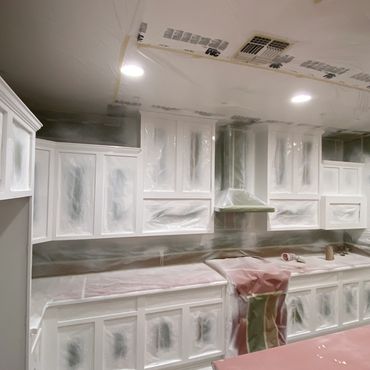 Kitchen cabinets covered in plastic for painting or renovation.