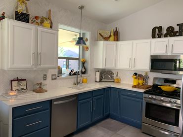 Modern kitchen with blue and white cabinets and yellow accents.