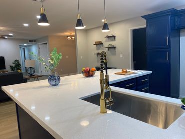 Modern kitchen island with gold faucet, blue cabinets, and pendant lights.