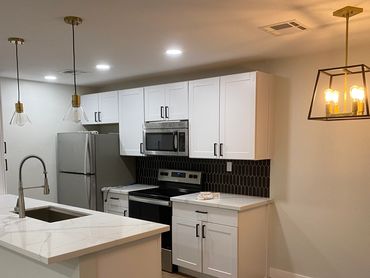 Modern kitchen with white cabinets, black backsplash, and pendant lighting.