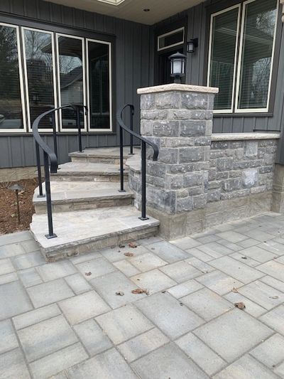 Modern stone steps with black iron railings leading to a patio door.