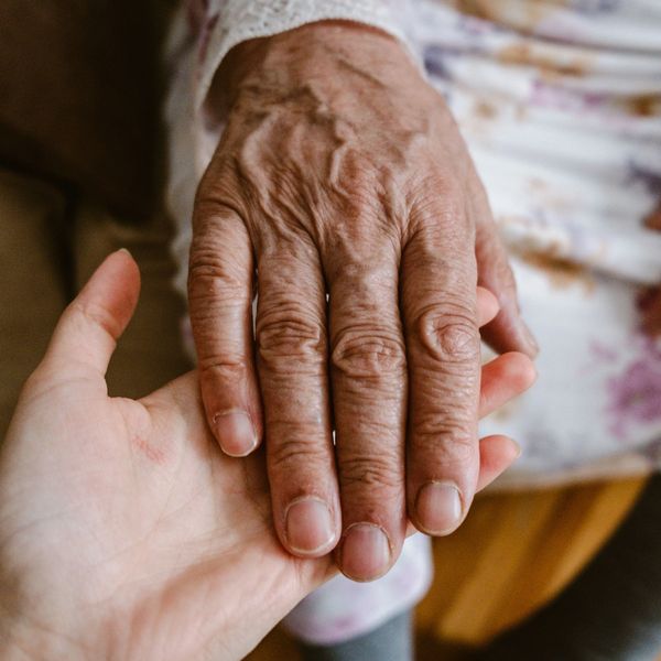The hand of an old person in the hand of a young person