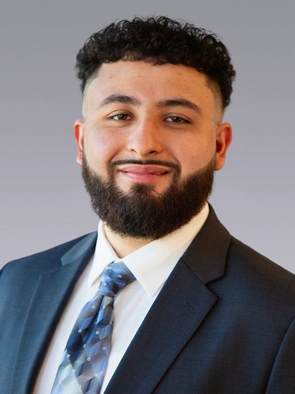 Professional young man with a beard in a suit and patterned tie.