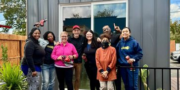 Members posing in front of the community-built mini home project