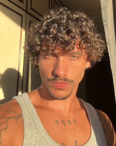 Young man with curly hair in sunlight.