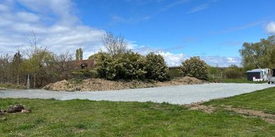 A gravel driveway surrounded by grass and bushes on a sunny day.