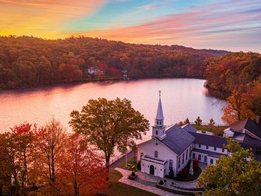 A serene church beside a lake during autumn sunset.