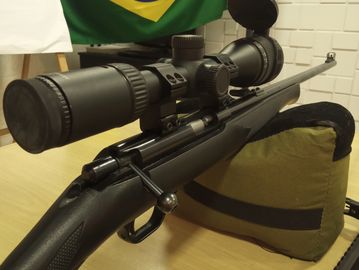 A sniper rifle with a large scope resting on a sandbag.