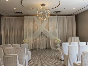 Elegant indoor wedding setup with white chairs and floral decorations.