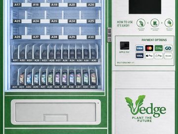 A modern vending machine with digital payment options and plant-based branding.