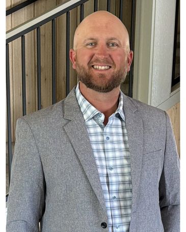 Man in gray blazer smiling indoors.