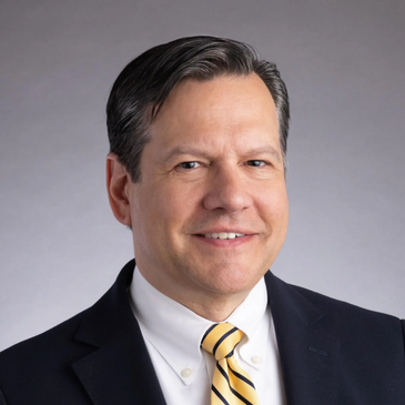 Professional portrait of a smiling man in a suit and striped yellow tie.