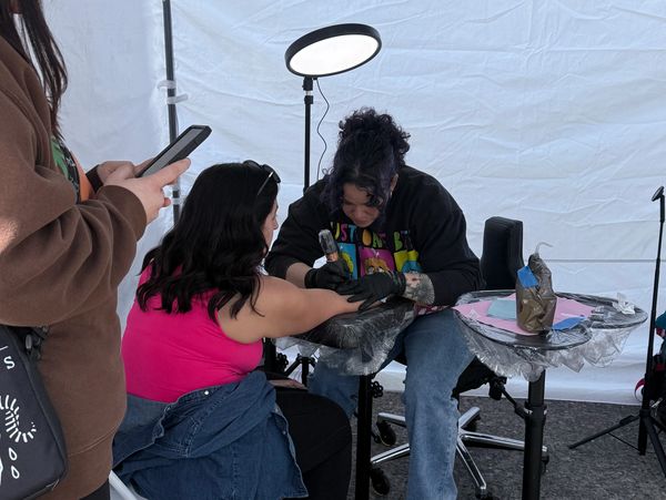 Tattoo artist working on a client inside a tent.