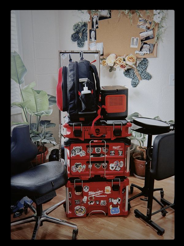 Stack of red Milwaukee toolboxes with stickers in a workspace.