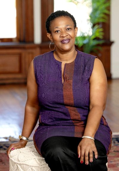A woman in a purple dress sitting indoors, smiling at the camera.