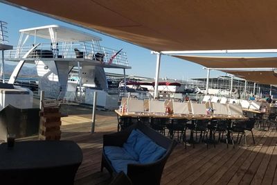 Outdoor dining area by the marina with boats docked nearby.