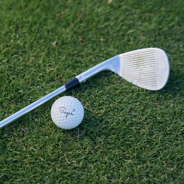 A golf club and ball on green grass ready for a shot.