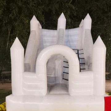 White inflatable castle on a yellow mat in an outdoor setting at night.