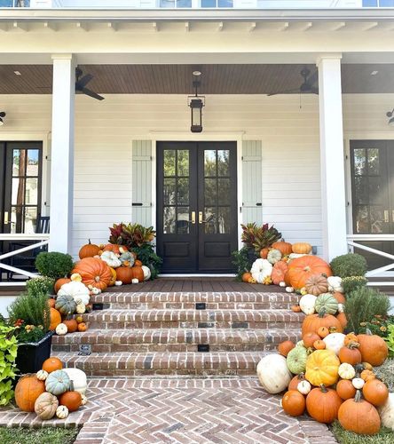 Front porch decorated with a variety of pumpkins and greenery for fall.