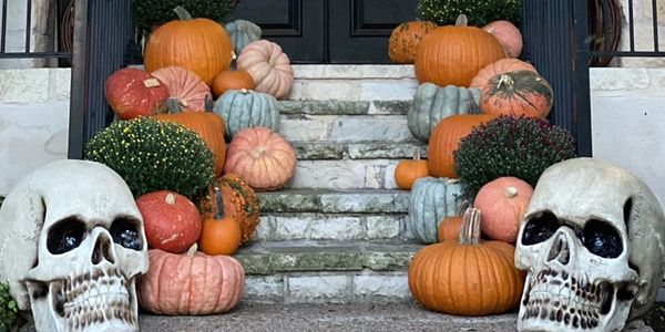 Front porch decorated with pumpkins, skulls, and fall wreaths for Halloween.
