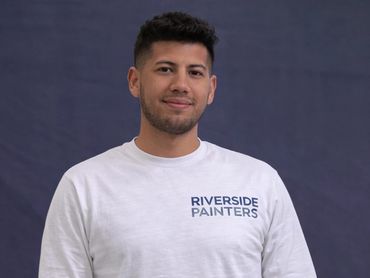 Man wearing a white long-sleeve shirt with Riverside Painters logo.
