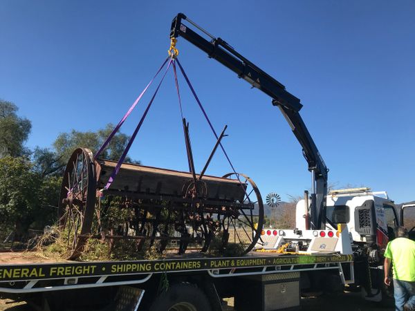 Crane carefully moving a very old plough