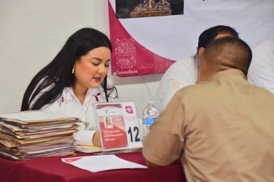 Mujer atendiendo a un hombre en mesa de registro.