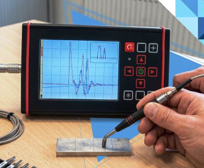 A person using a handheld device to test a metal piece with displayed waveforms on screen.