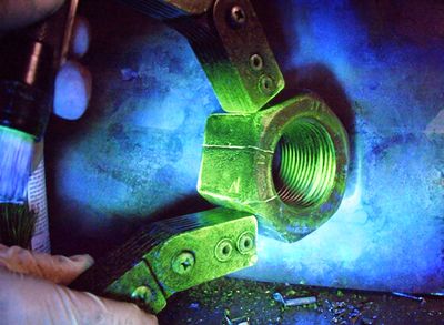 Inspection of a cracked metal nut using a UV light and a magnetic particle inspection tool.