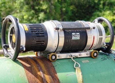 NDT Tools device mounted on a green metal pipe for industrial testing.