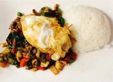 Fried egg served on a bed of stir-fried vegetables and rice.