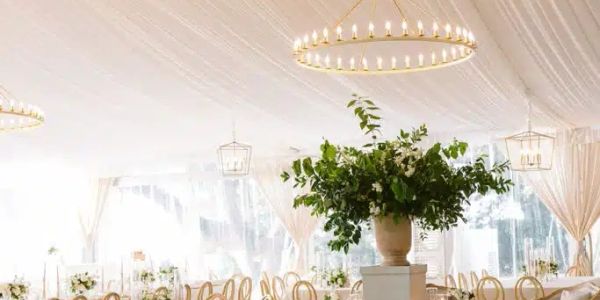 Elegant white event tent with chandeliers and floral centerpiece.