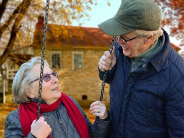 Elderly couple sharing a warm moment on a swing in autumn.