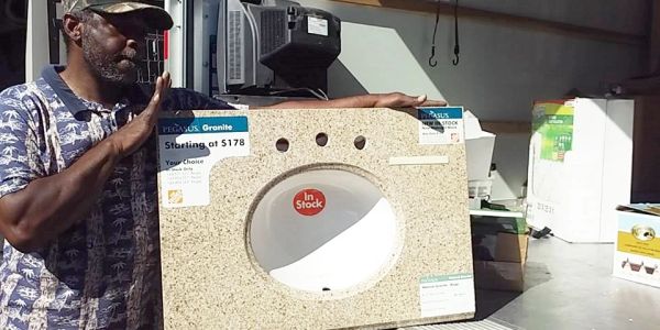 Man holding a granite countertop with a sink cutout.