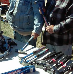 Two people holding and displaying hammers at a table.