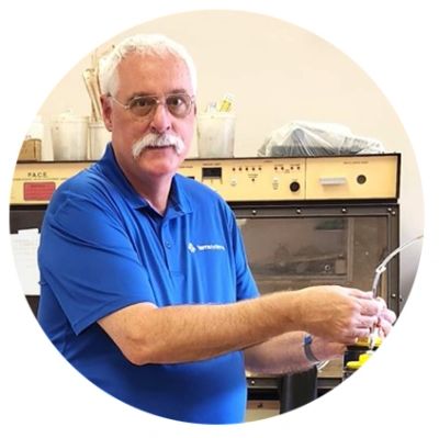 Man in blue shirt holding a tube in a lab setting.