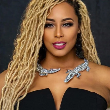 Confident woman with blonde dreadlocks in a black strapless dress and statement necklace.