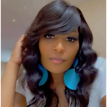 Woman with wavy black hair and large blue earrings posing for a selfie.